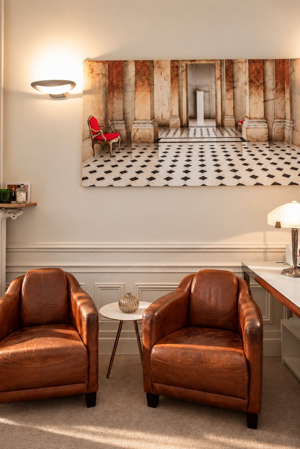 Deux fauteuils de cuir côte à côte dans un salon du cabinet, sous une grande photographie d’architecture