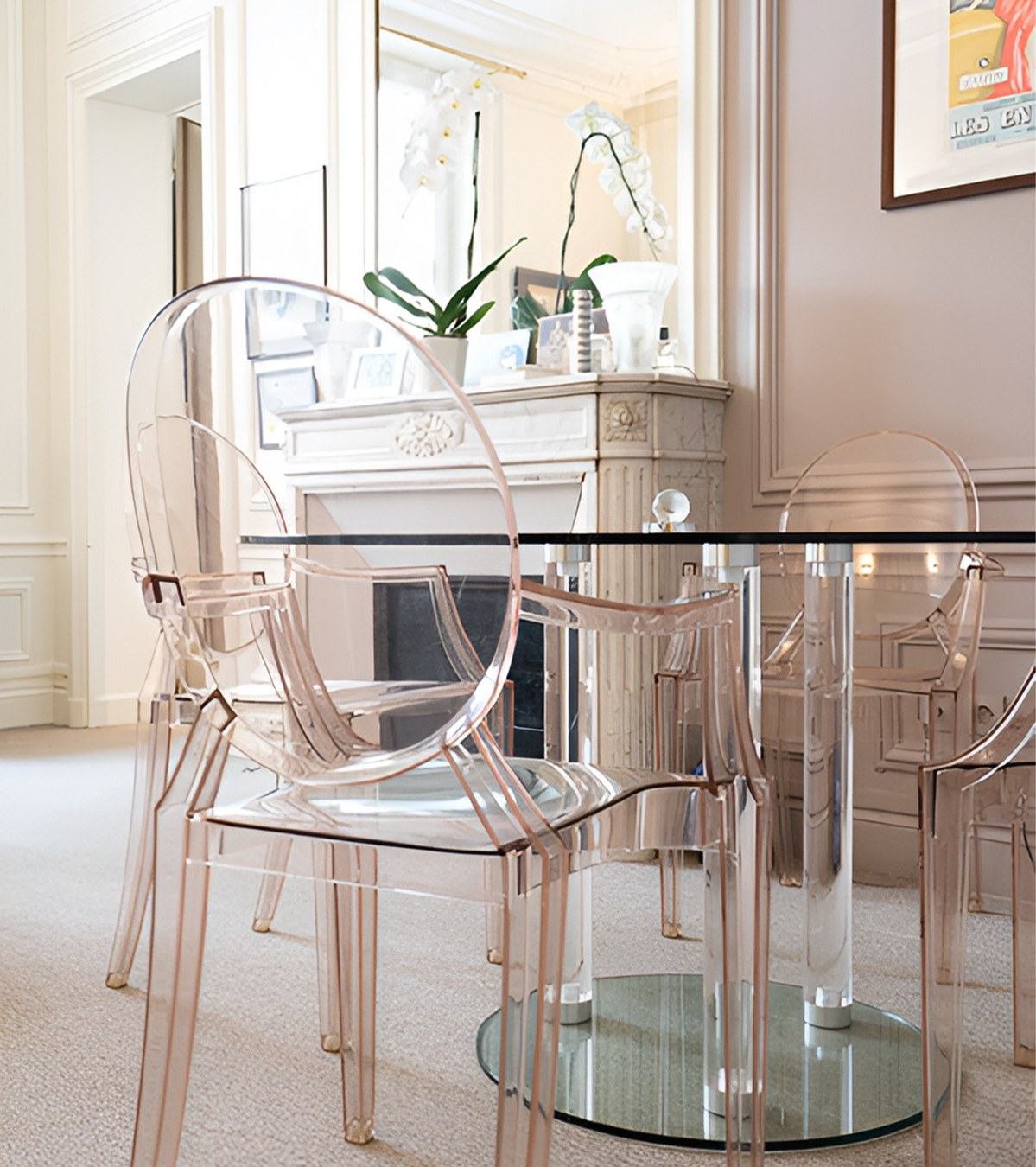 Le salon du cabinet : table de verre, chaises transparentes et cheminée de marbre